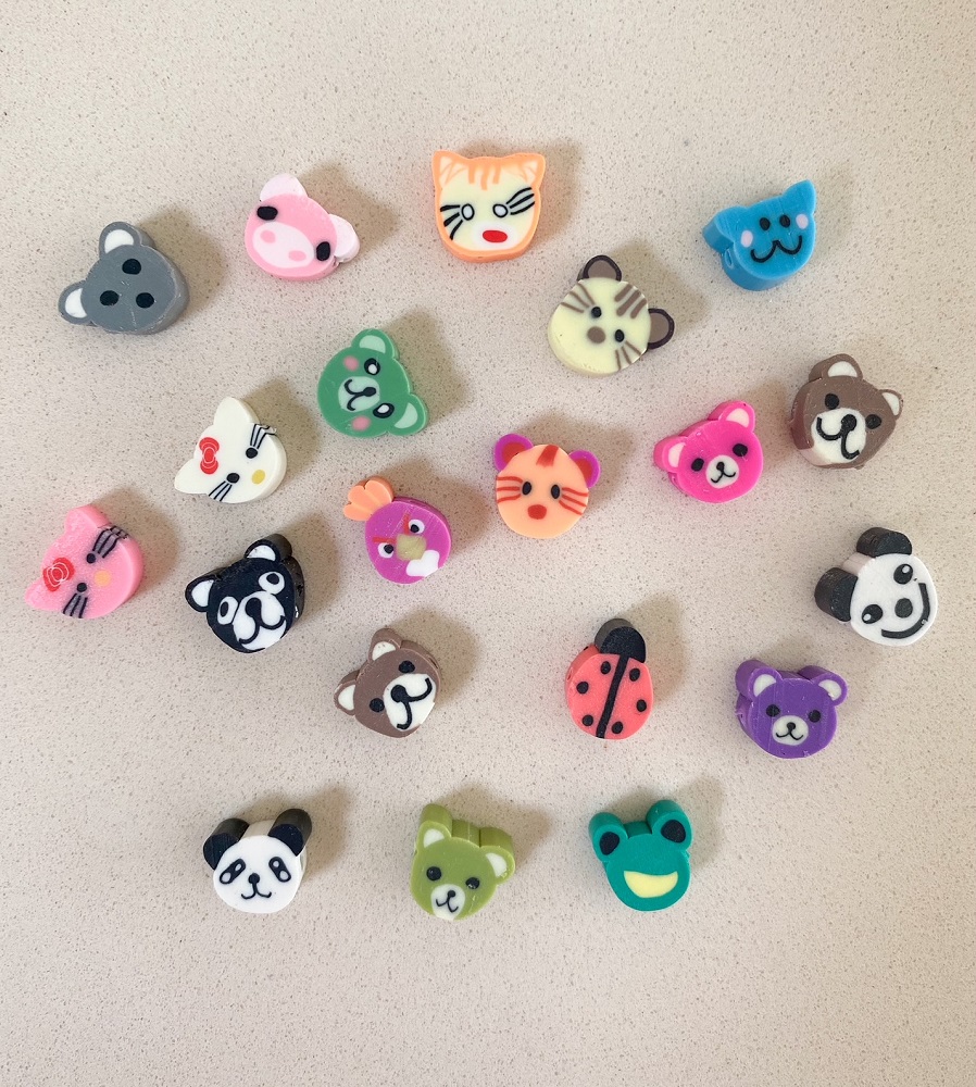 Bunte Radiergummis, Tiermotive, Katze, Hund, Bär, Panda, Marienkäfer, Frosch, rosa, blau, grün, orange, lila, gelb, Cartoon-Stil.