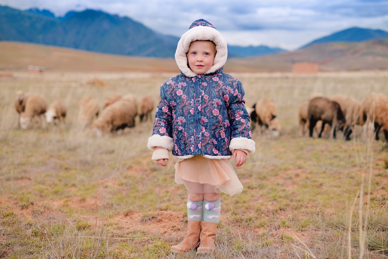 kidssocksmayumilichen2 Kindermantel, dunkelblau, Blumenmuster, Kapuze mit Kunstfell, Tüllrock, bunte Kniestrümpfe, braune Stiefel.