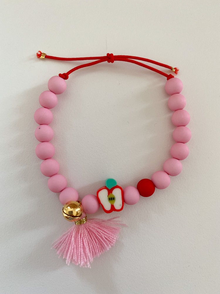 IMG_5478 Perlenarmband, pinke Kugeln, rotes Band, goldene Glöckchen, Apfelanhänger, pinke Quaste.