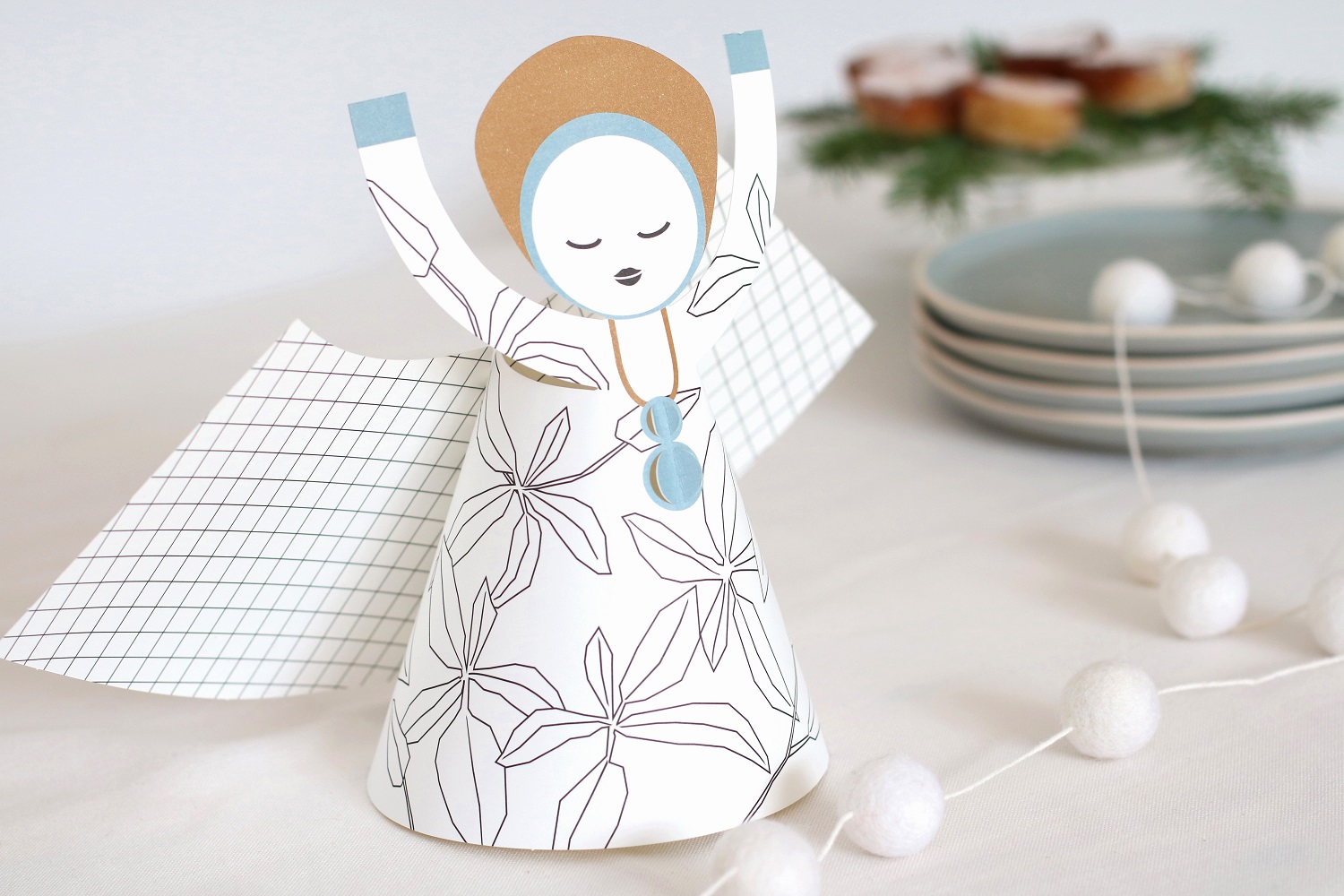 XL-angel-close Engelsfigur aus Papier, weiß mit schwarzen Blättermustern, blau-gemusterte Flügel, hellbrauner Heiligenschein, blaues Halsband.