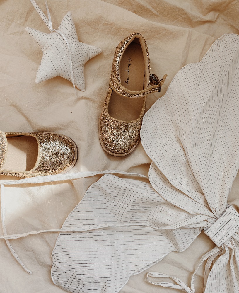 KS1933-MULTI-Extra-3 Glitzernde Kinderschuhe, goldfarben, Riemchenverschluss, Stoffsterne, beigefarbener Hintergrund.