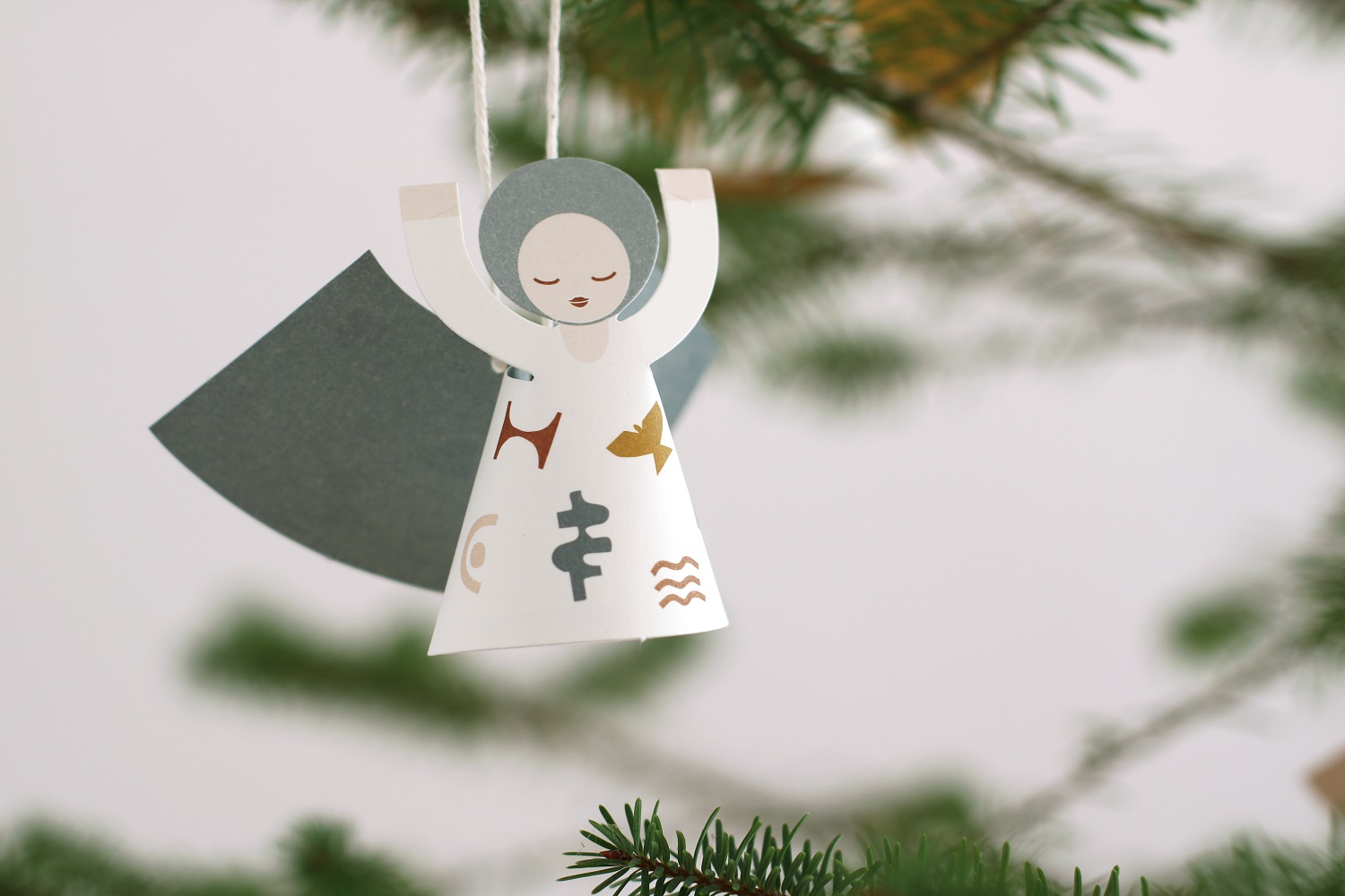 fridur-new-5 Hängender Engel aus Papier, weiß, dunkle Flügel, Aufdrucke in Braun und Schwarz, stilisierte Muster, Weihnachtsbaumdeko.