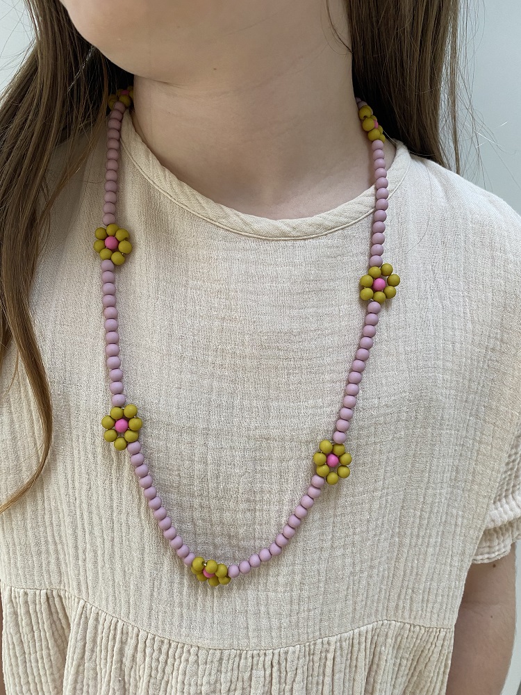 IMG_4909 Halskette aus kleinen rosa Perlen und gelben Blumenperlen, getragen über beige Oberteil.