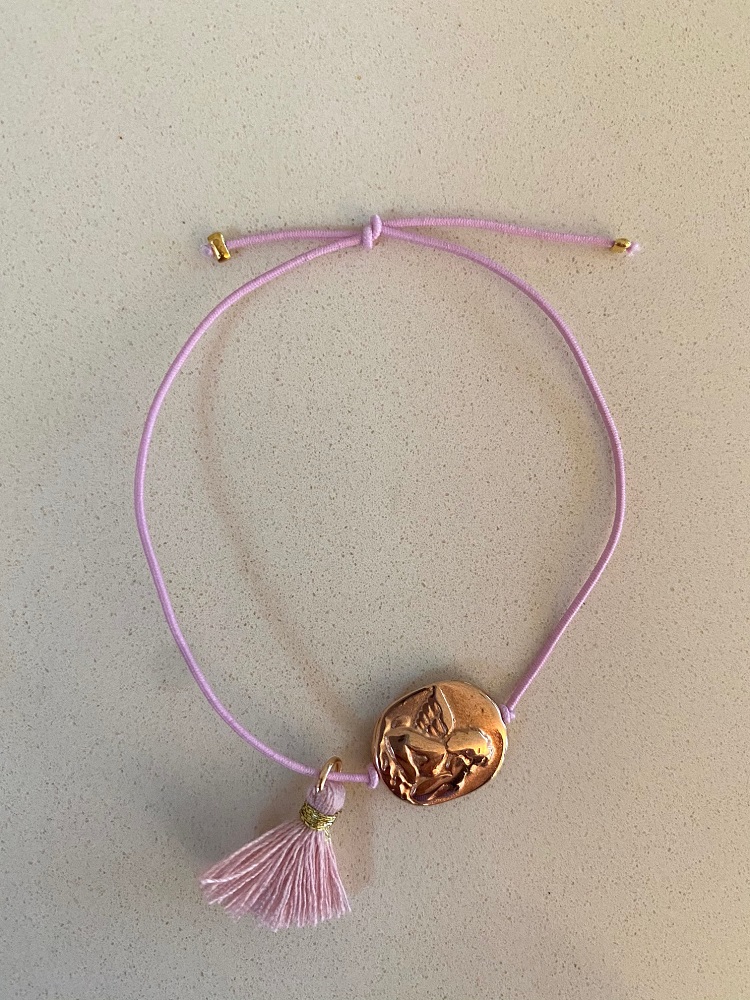 IMG_0861 Armband; hellviolette Schnur; bronzefarbene Medaille mit Relief eines Kindes; rosa Quaste; goldene Details an den Enden.