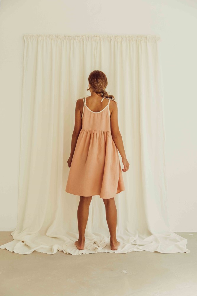 liss23_076_W_louisa-dress_peach_back3 Peachfarbenes Sommerkleid, ärmellos, Träger, lockerer Schnitt, knielang, Rückansicht, weißer Hintergrund.