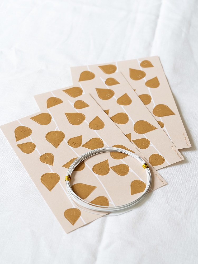 twig-leaves-ochre-4 Papierblätter mit goldbraunem Blättermuster; darunterliegend, silberne Drahtrolle mit gelben Bindungen.