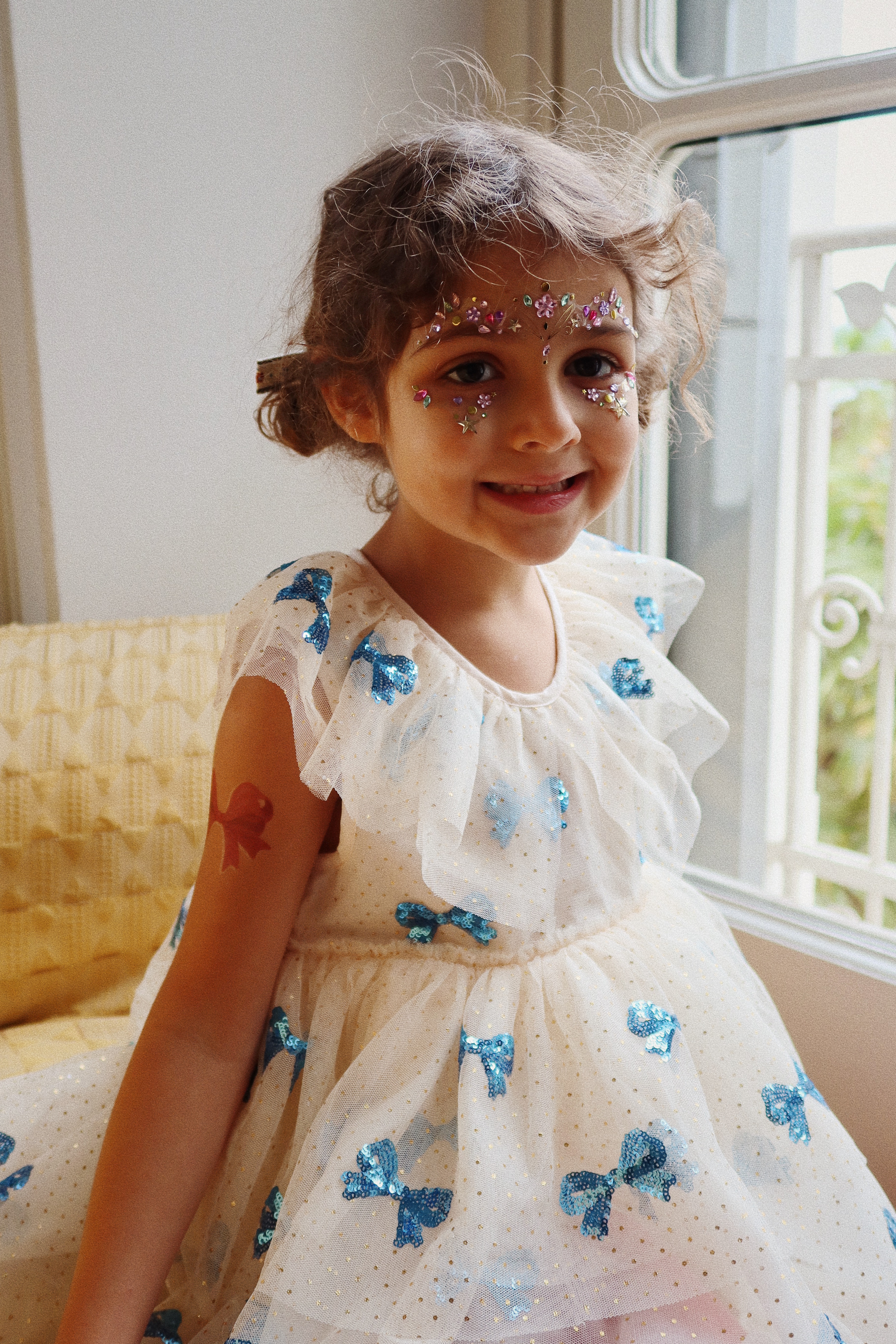 Kinderkleid, weiß, blaue Pailletten-Schleifen, Rüschenärmel.