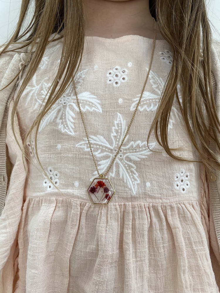 IMG_2613CRQvZHDLVlB3j Hexagonale Kette, goldene Kette, Anhänger mit roten und violetten Blüten, rosa Kleid mit weißer Stickerei, florales Muster.