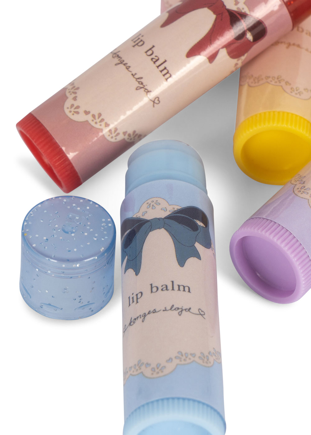 Lippenbalsam in Stiftform, verschiedene Farben, Aufdruck mit Schleifenmotiv, transparenter Deckel mit Glitzerpartikeln, Aufschrift "lip balm".