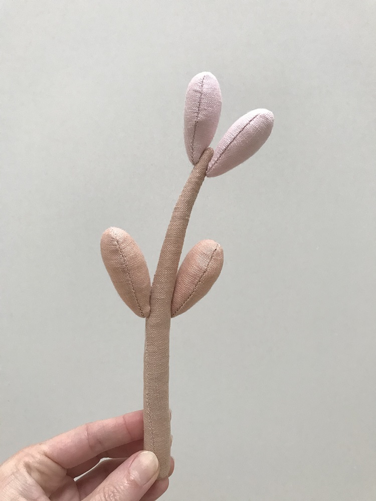 IMG_1112-002 Stoffspielzeug, abstrakte Pflanze, beige und rosa, wattiert, zwei beige Blätter unten, zwei rosa Blätter oben, handgehalten.