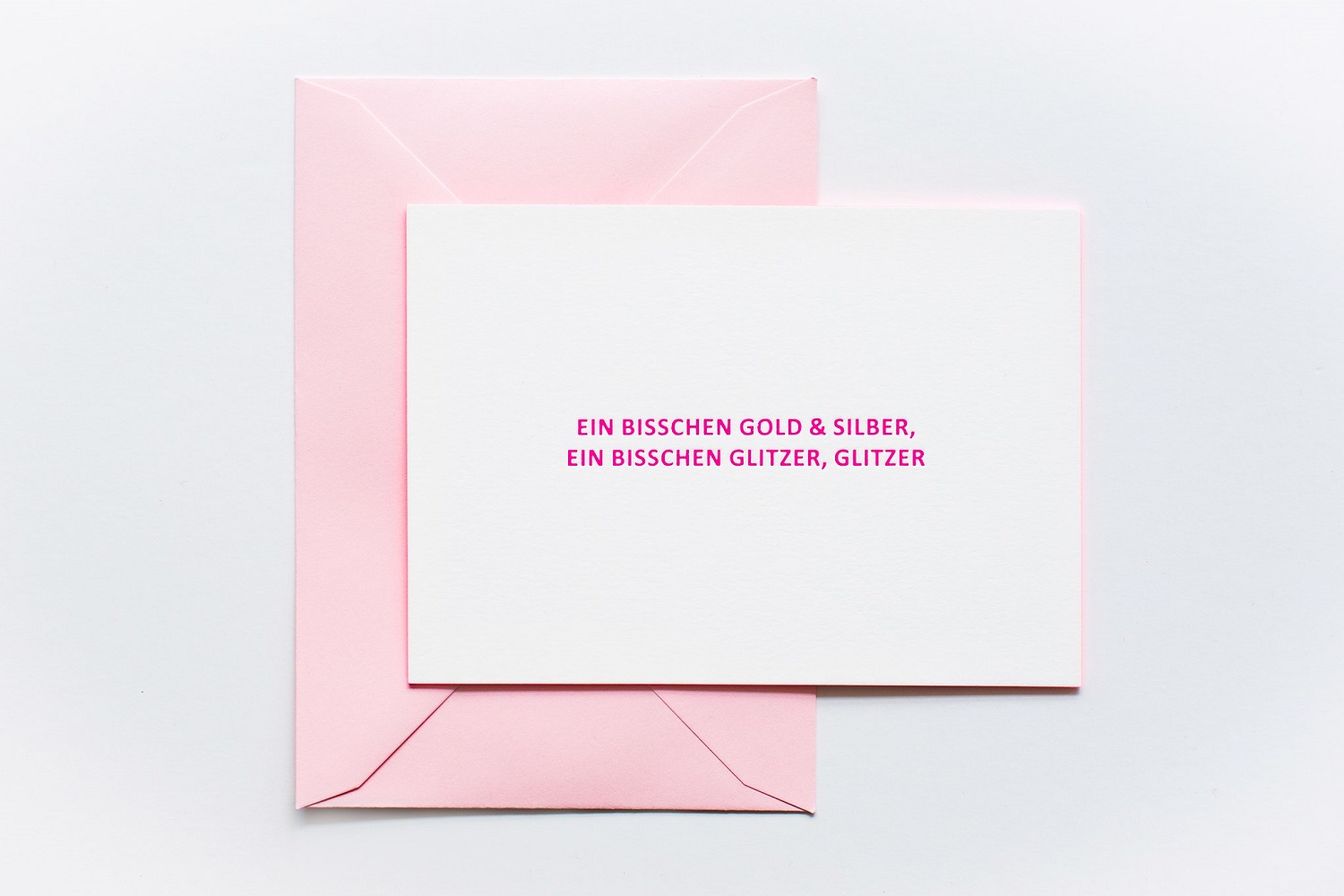 7a75ef_efcd294e9dfb43da998fb9446e1e5109_mv2_d_4989_3326_s_4_2 Grußkarte, weiß, rosa Umschlag, Aufdruck: „Ein bisschen Gold & Silber, ein bisschen Glitzer, Glitzer“, pinke Schrift.