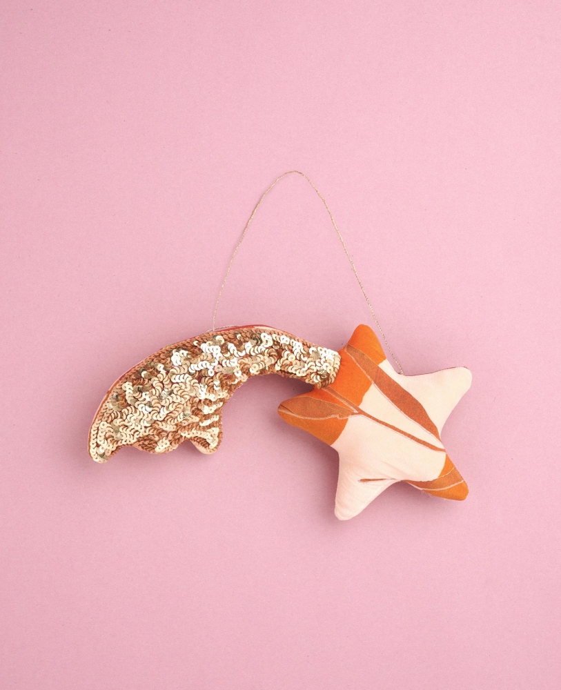 Shooting-Star-SILK-Ornament-Flamingo Plüschstern-Anhänger, goldene Pailletten am Schweif, orange-weiß gemusterter Stern, rosafarbener Hintergrund.
