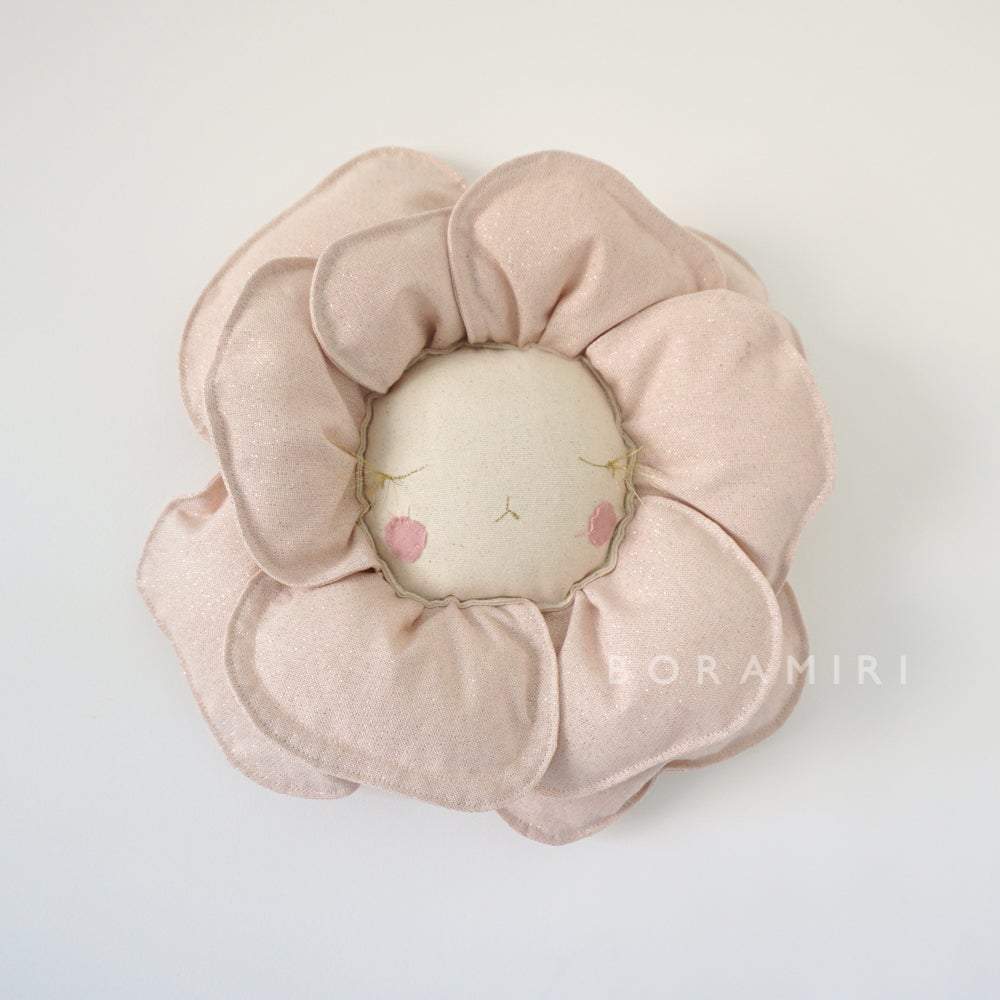 fleurRV_3_web_1024x1024-2x Kissen, blumenförmig, pastellrosa Blütenblätter, Gesichtsstickerei mit geschlossenen Augen, rosa Wangen, cremefarbenes Zentrum, Stofftextur.