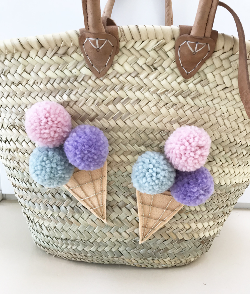 IMG_2321 Korb, beige, mit braunen Griffen, dekoriert mit bunten Pom-Pom-Eiswaffeln in Rosa, Lila, Hellblau.