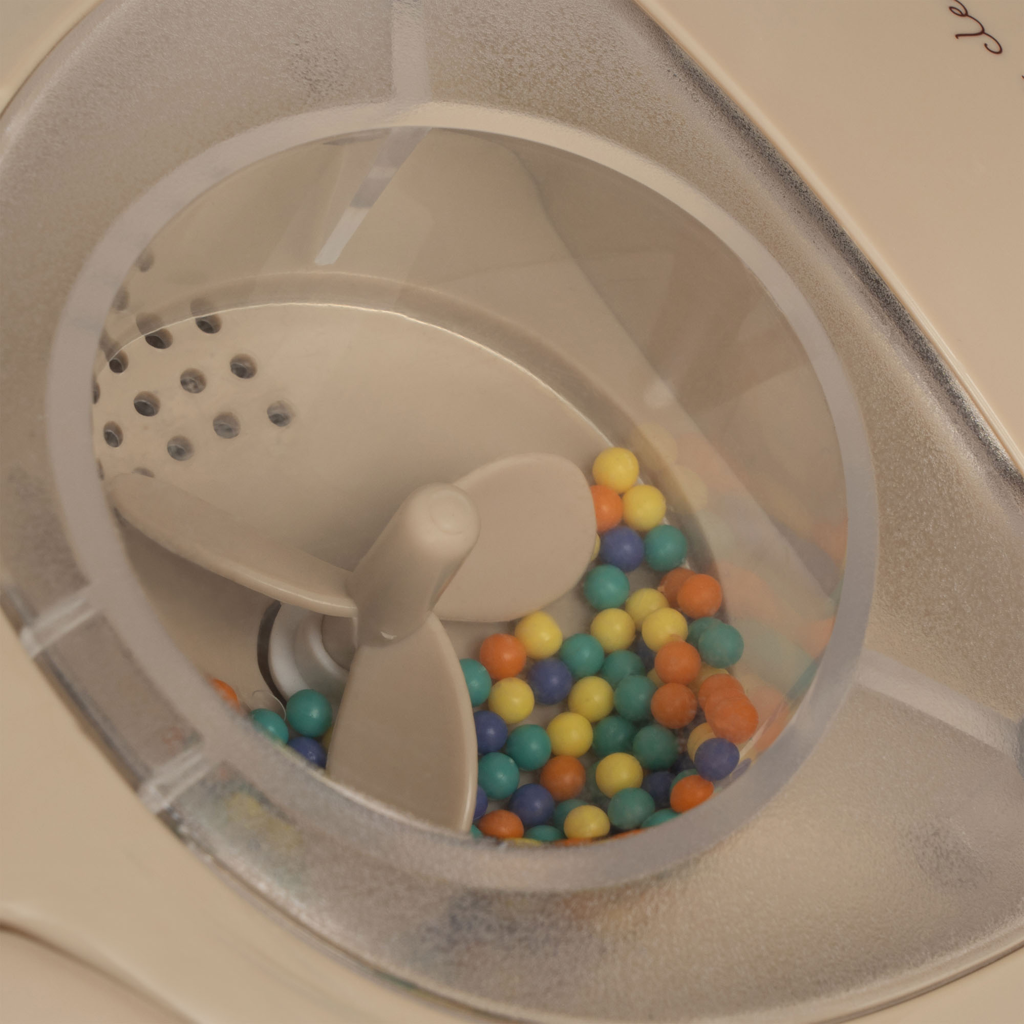 Eismaschine, beige, runde transparente Abdeckung, bunte Kugeln im Behälter, beige Rührblätter.