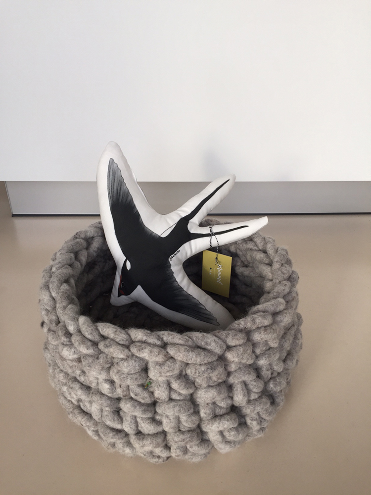 IMG_8261 Gehäkelter Korb, grau, mit Stoffvogel-Kissen, schwarz-weiß, Etikett am Kissen befestigt.