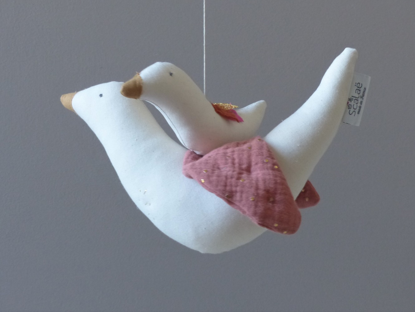 P1210972 Stofftier, fliegende Gans, weiß, rosafarbene Flügel mit goldenen Punkten, gelber Schnabel, Aufhänger, Etikett "Scalaë".