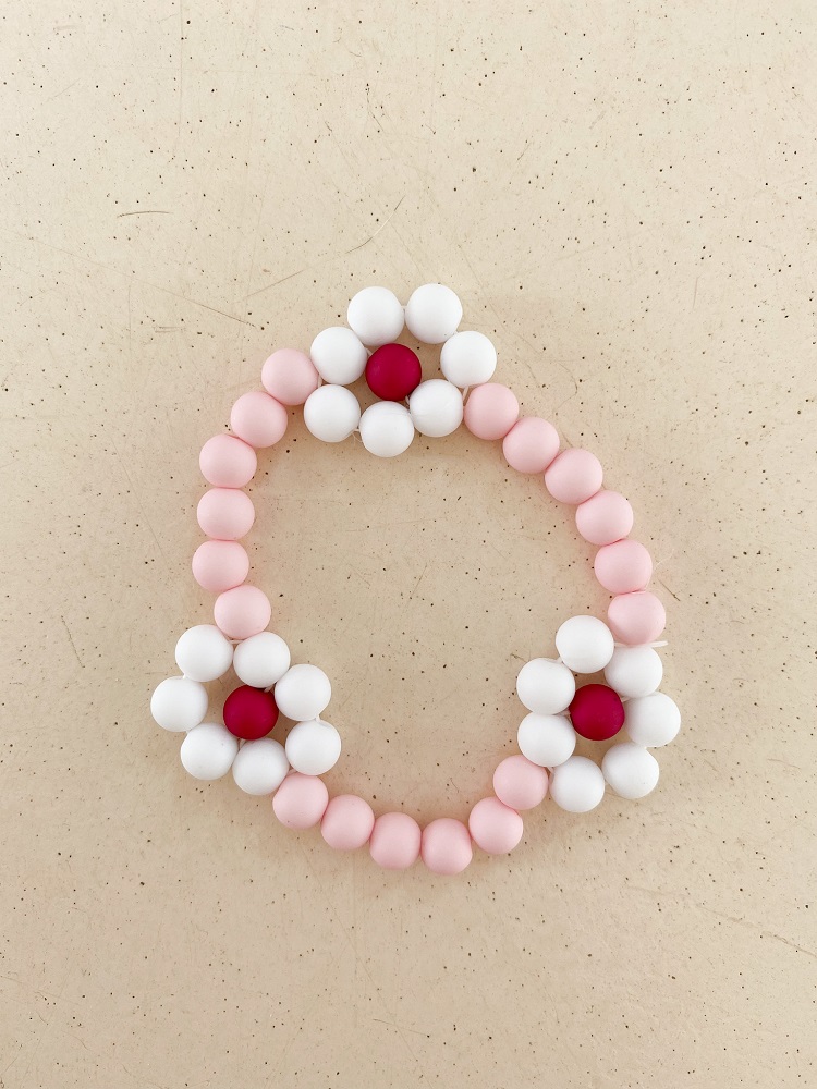 IMG_4996 Armband, rosa Kugeln, drei weiße Blumenmuster, rote Zentren, Gummiband.