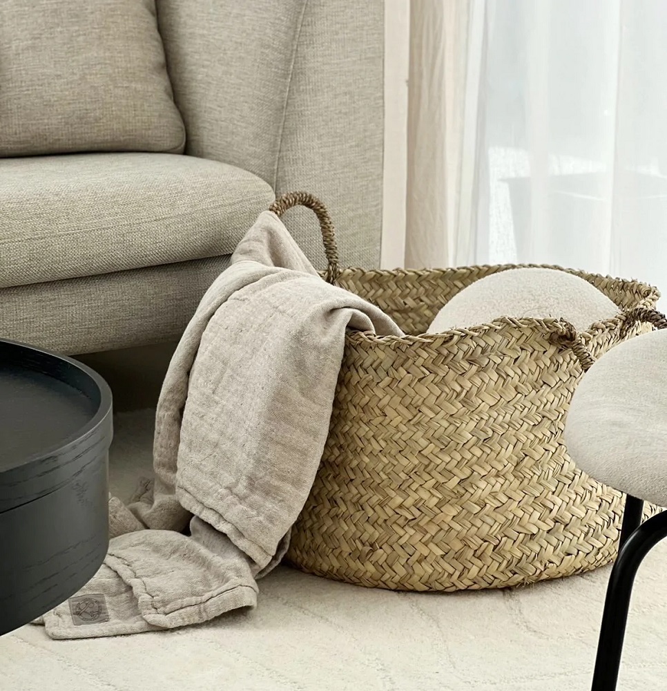 1170x1170_05_1024x1024-2x Korb aus geflochtenem Naturmaterial, beige Decke, Sofa aus grauem Stoff, Holztisch schwarz, Textur der Decke weich, Korb rund mit Henkeln.