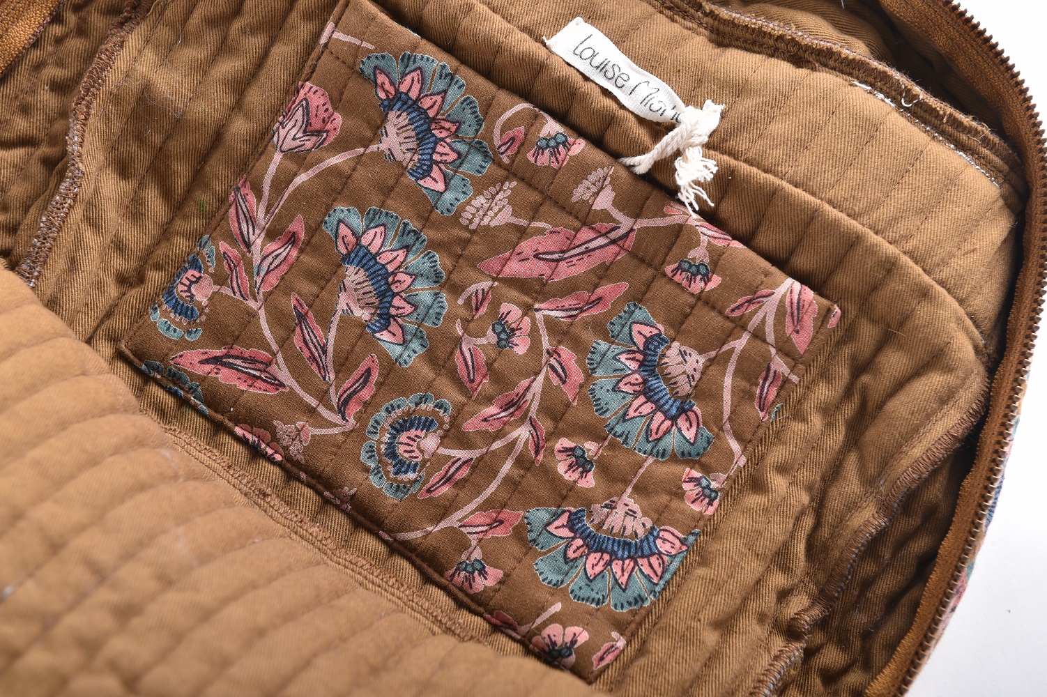 Girls-Backpack-Arti-BronzeFolkFlowers-6 Braune Jacke, Innenfutter gesteppt, florales Muster in Pink und Blau, helles Etikett.