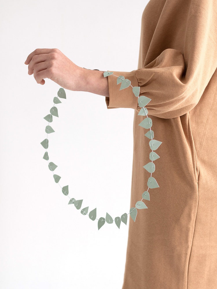twig-leaves-sage-green Papiergirlande, blassgrün, Blattform, von Hand gehalten.