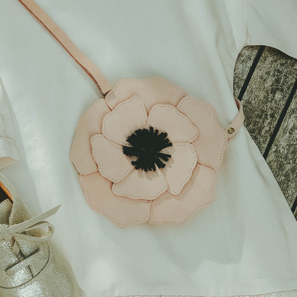 Bags-Purses-Crop-Media-kit-SS2220 Umhängetasche, blumenförmig, rosa, schwarzes Detail in der Mitte, getragen über weißem Oberteil.