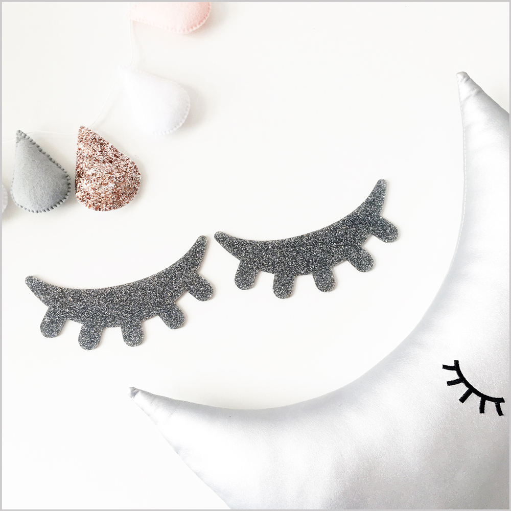 DEsilver3 Mondkissen silber, geschlossene Augen schwarz; Wanddekoration Wimpern glitzernd schwarz; Filzgirlande Tropfen pastellfarben.