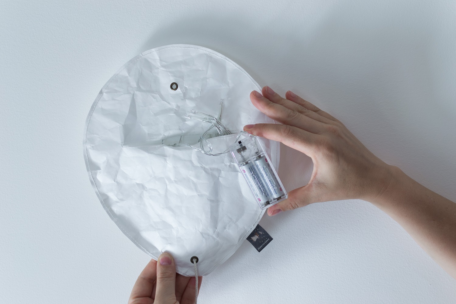 DSC_0518-2 Papierlampe, rund, weiß, Batteriefach transparent, enthält batteriebetriebene Lichterkette, weiße Wand.