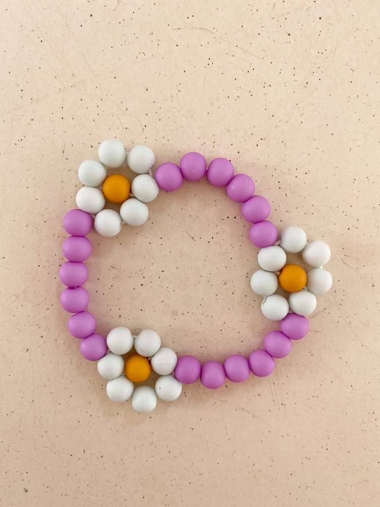IMG_4993 Armband aus lila Perlen, Blumenanhänger mit weißen Blütenblättern, gelber Blütenstempel.