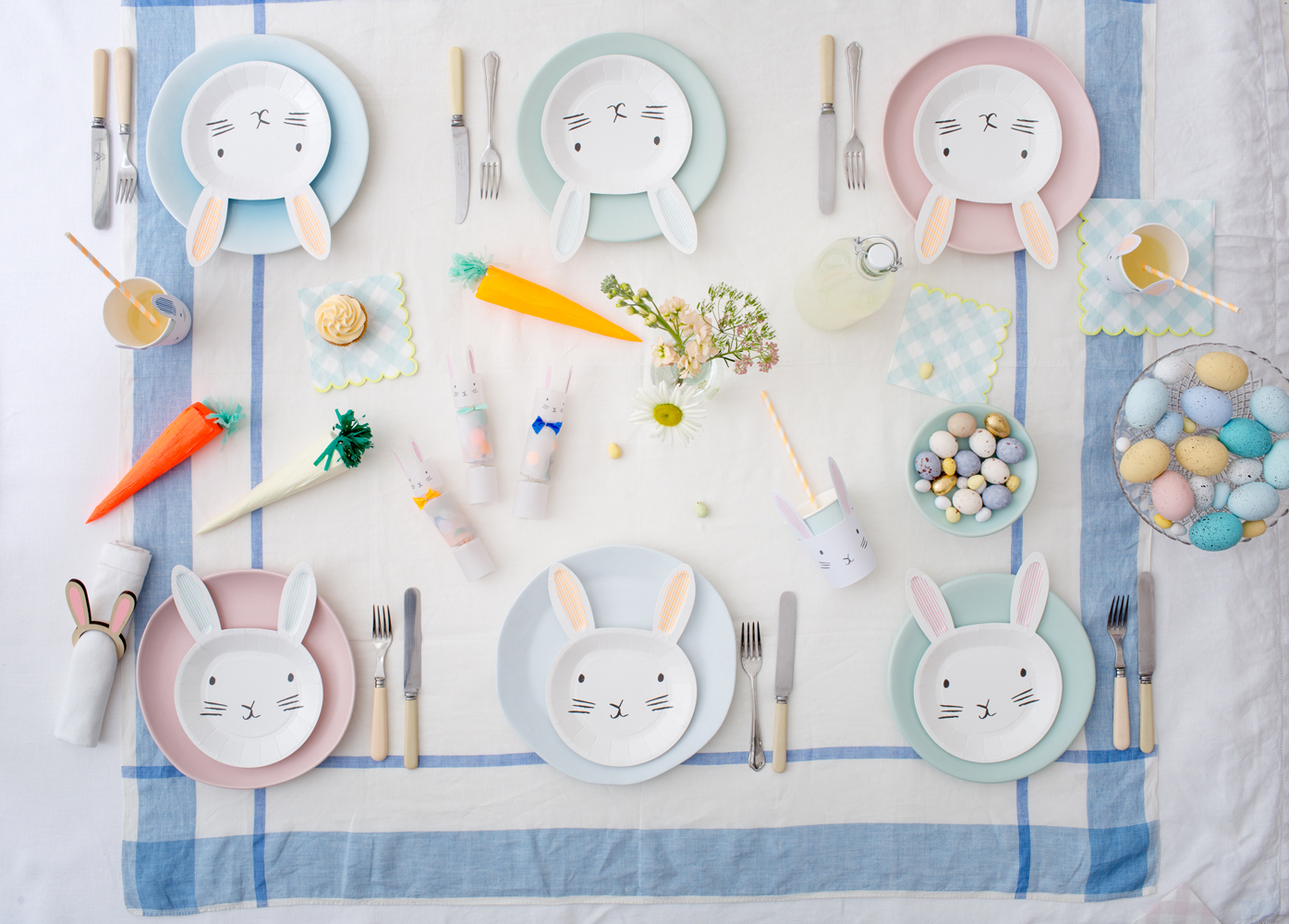 MM2018_Spring_Easter_05 Papiergeschirr, hellblau und rosa, Häschenmotiv mit Ohren, pastellfarbene Teller, Ostereier, Möhren-Dekoration, Besteck in Pastellfarben, Servietten mit Hasenohren, Blumenarrangement, Trinkbecher mit Häschenaufdruck.
