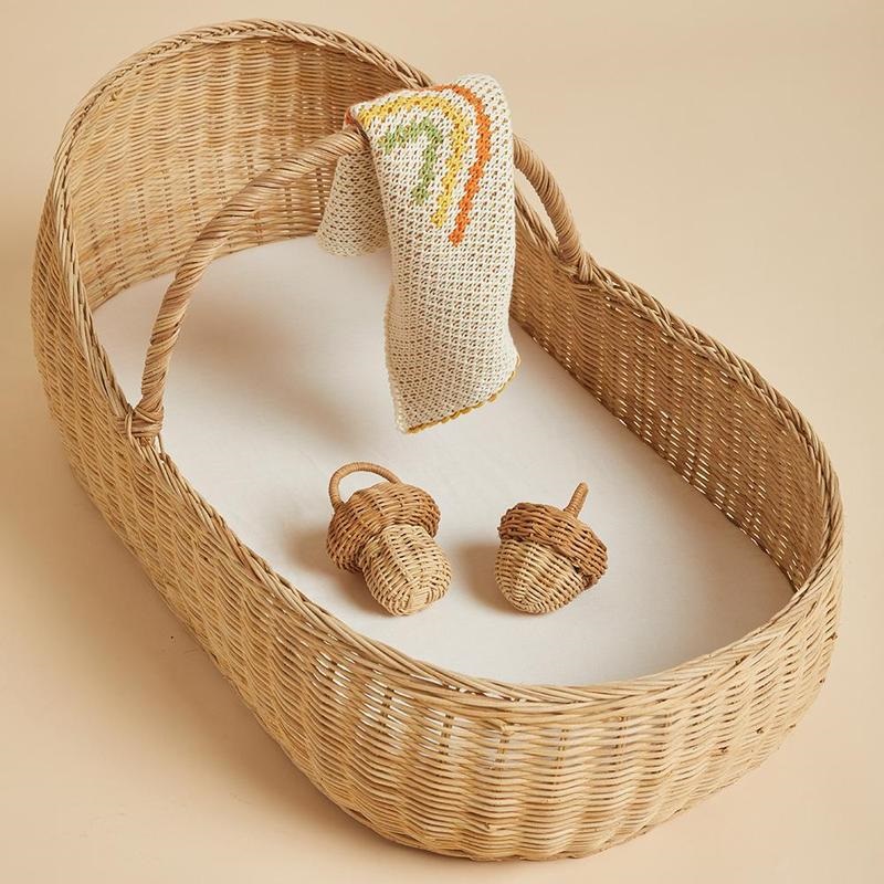 OE-Lyra-Moses-Basket-Rattles-Blanket_1b4b9982-d87e-4fdb-a6cb-059f14f89350_800x Weidenkorb für Babys, naturfarben, mit weißer Unterlage; kleines gestricktes Tuch mit Regenbogenmotiven; zwei Rasseln in Form von Eicheln, aus geflochtenem Material.