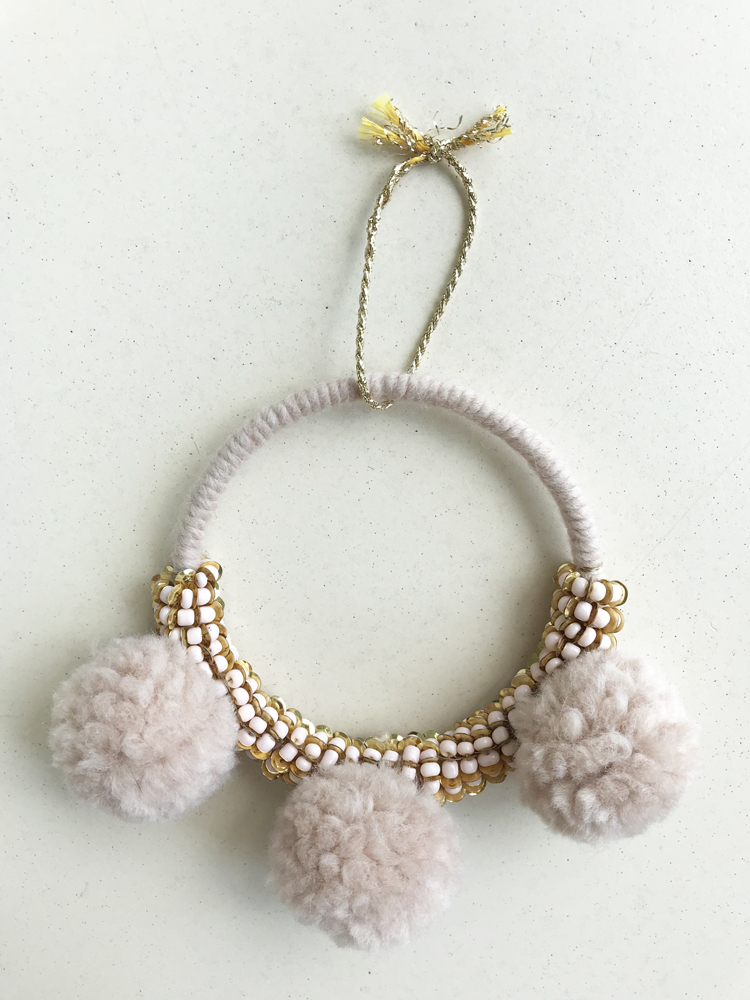 IMG_2853 Stoffkranz, beige, drei flauschige Pompons, weiße und goldfarbene Perlenverzierung, goldene Aufhängeschlaufe.