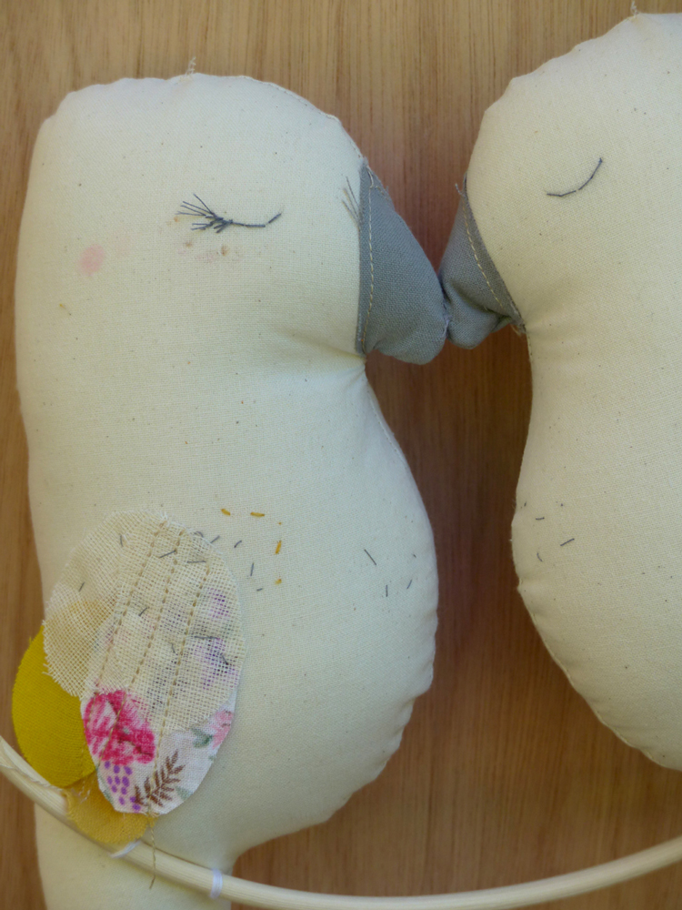 Scala-Maya-couple-de-perruches2 Stofftiere, Vogelmotiv, Cremefarbe, grau-rosa Details, gestickte Augen, bunte Flügel, Holzuntergrund.